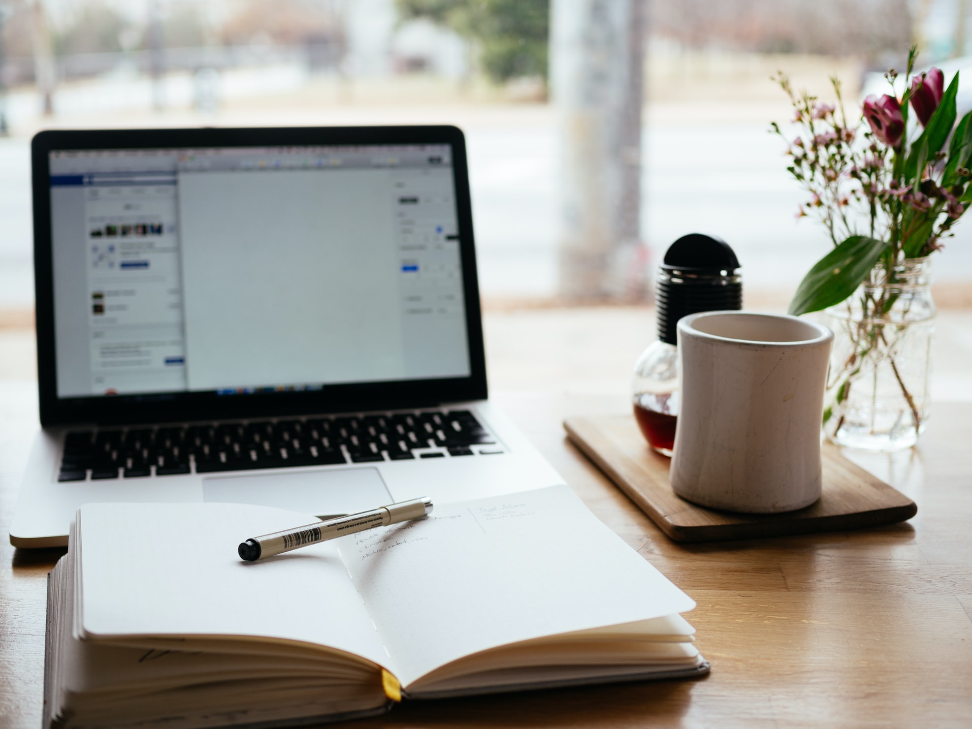 Desk with a laptop, notepad, and coffee